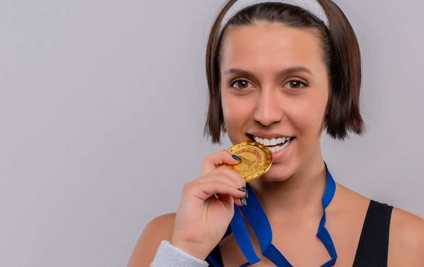 Joven con medalla deportiva sonriendo relación entre el deporte y la salud bucodental