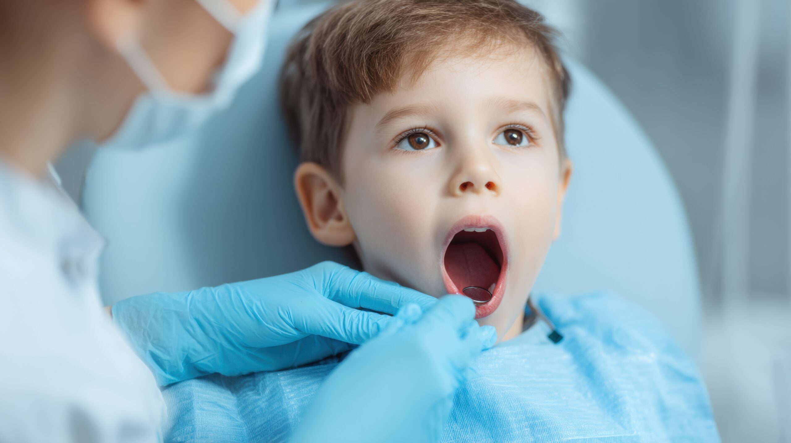 Dentista revisando la boca de un niño en la consulta de odontopediatría