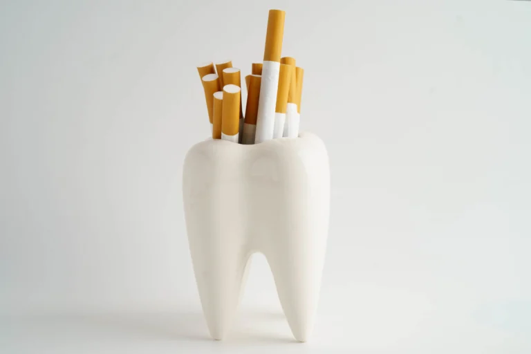 Cigarrillos junto a un cepillo de dientes sobre fondo neutro
